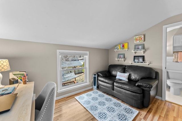 living area featuring vaulted ceiling, baseboards, and wood finished floors