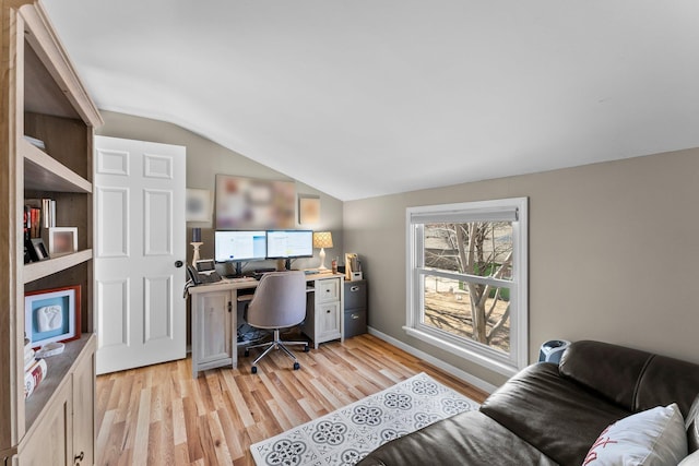 office space with vaulted ceiling and light wood-style flooring