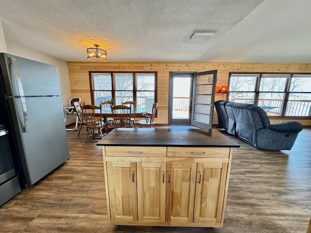 28887 Hi Vista Dr, Otter Tail Twp, MN 56515 - kitchen with freestanding refrigerator, a textured ceiling, dark countertops, dark wood-type flooring, and wood walls