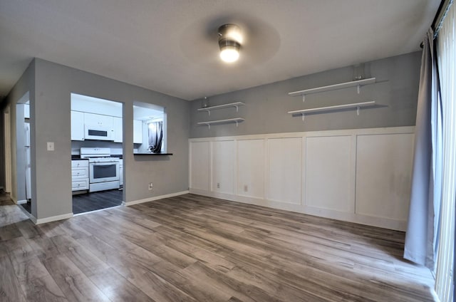 kitchen featuring a ceiling fan, dark countertops, wood finished floors, white appliances, and white cabinets