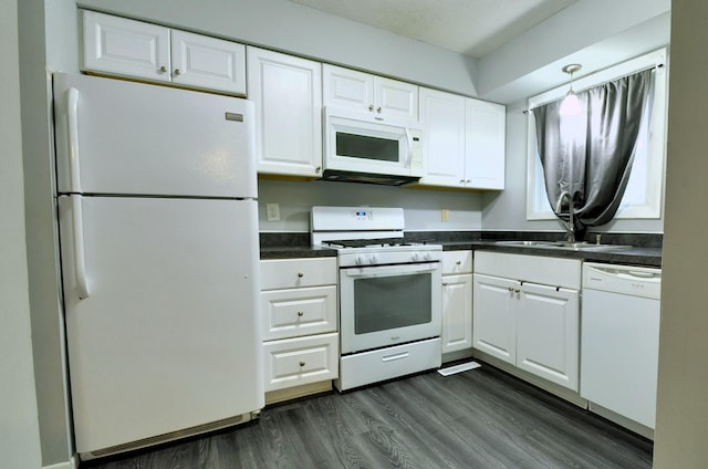 kitchen with white appliances, dark countertops, and white cabinets