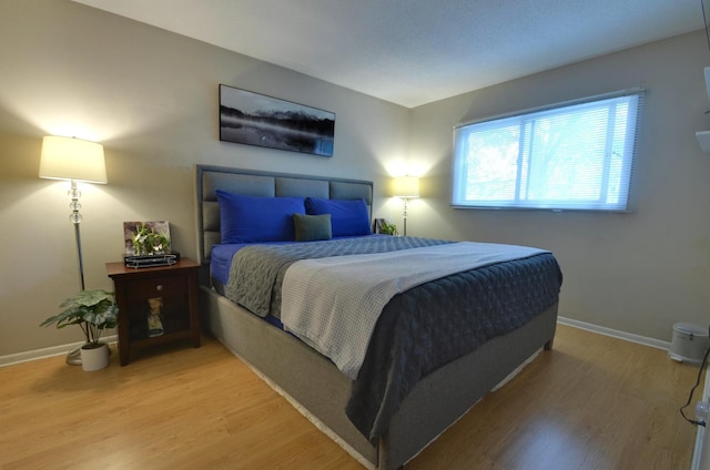 bedroom featuring light wood finished floors and baseboards