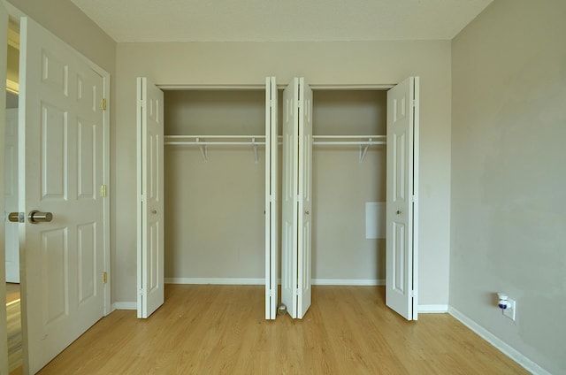 unfurnished bedroom with light wood-style floors, multiple closets, and baseboards