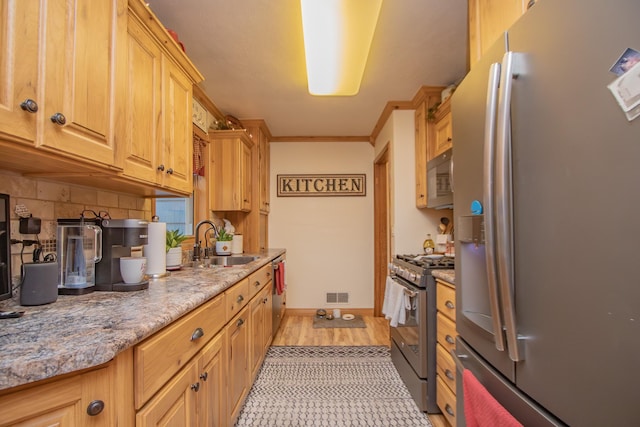 kitchen with crown molding, baseboards, decorative backsplash, stainless steel appliances, and a sink