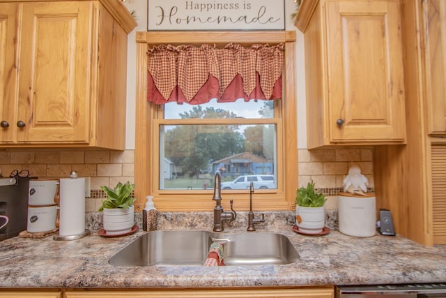 kitchen with tasteful backsplash, light brown cabinets, light stone countertops, dishwasher, and a sink