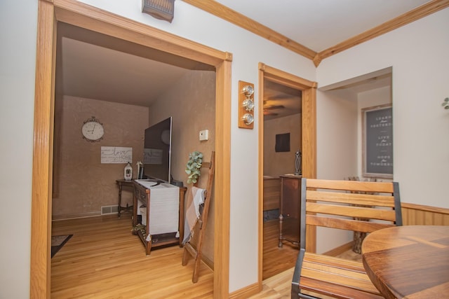 corridor with visible vents, light wood-style flooring, baseboards, and ornamental molding