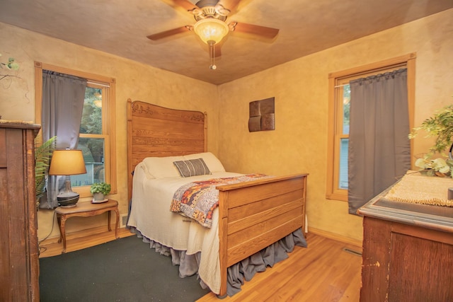 bedroom with a ceiling fan, baseboards, and wood finished floors