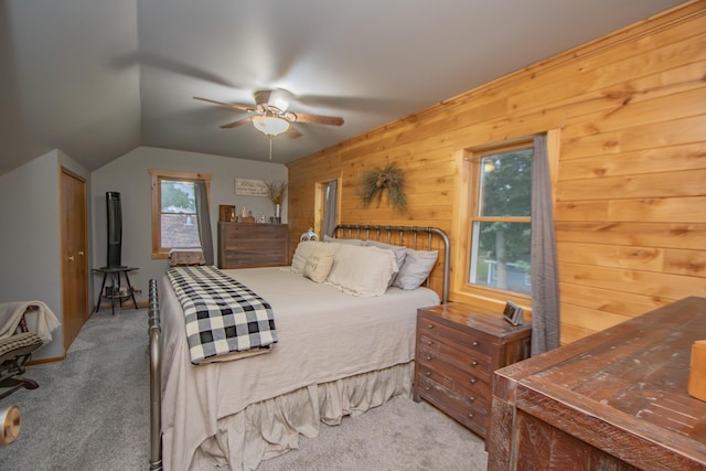 bedroom with lofted ceiling, wooden walls, carpet flooring, and a ceiling fan