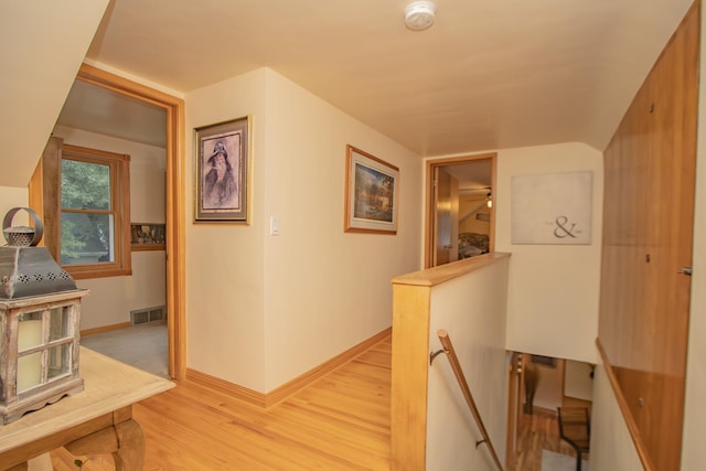 hall featuring an upstairs landing, visible vents, light wood-type flooring, and baseboards