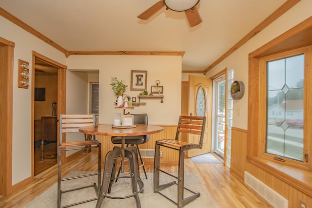 dining space with visible vents, wainscoting, crown molding, and light wood-type flooring