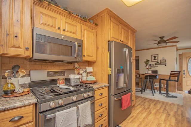 kitchen with light wood-style flooring, a ceiling fan, backsplash, appliances with stainless steel finishes, and crown molding