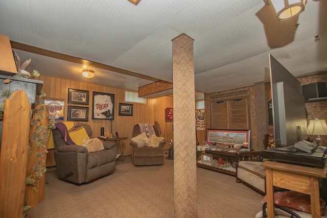 carpeted living room featuring wooden walls and decorative columns