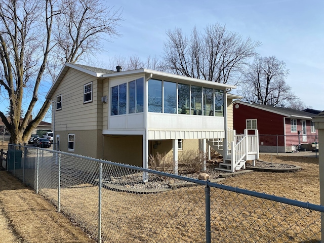 back of house with fence, driveway, and a sunroom