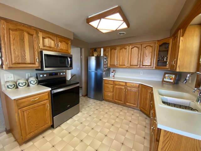 kitchen with light countertops, light floors, brown cabinets, and stainless steel appliances