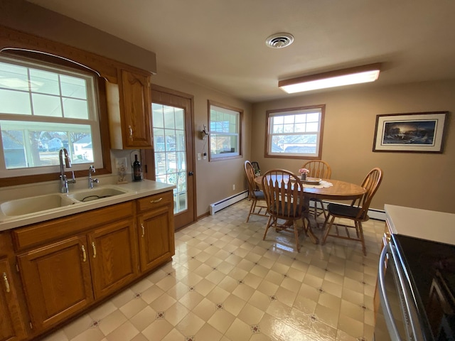 kitchen with visible vents, light floors, baseboard heating, brown cabinetry, and a sink