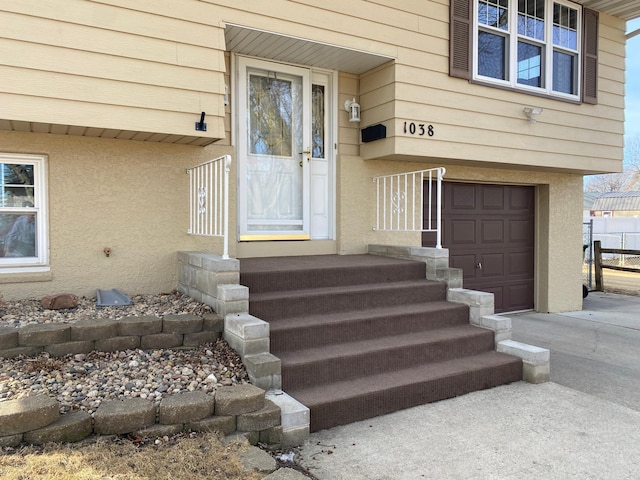 property entrance featuring stucco siding, driveway, and a garage