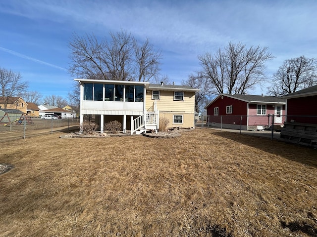 back of property with a lawn, a fenced backyard, and a sunroom