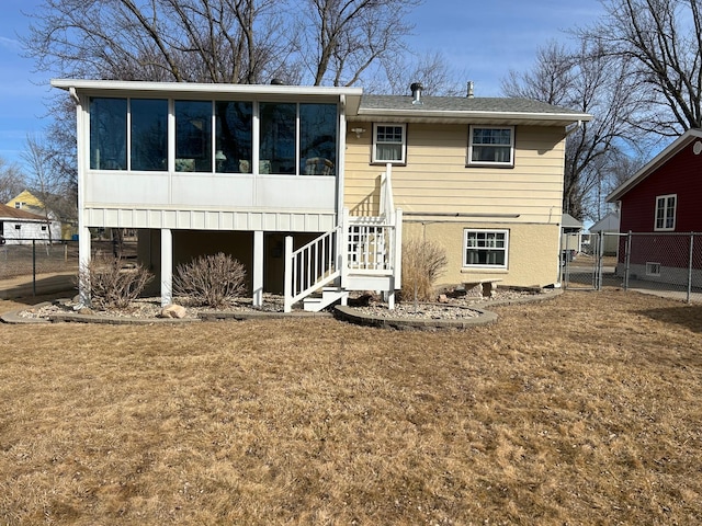 back of house featuring a lawn, a gate, fence, a sunroom, and stairs