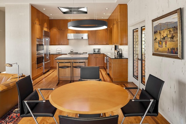 5123 Lake Ridge Rd, Edina, MN 55436 - kitchen with a sink, a center island, light wood-style floors, wallpapered walls, and brown cabinetry