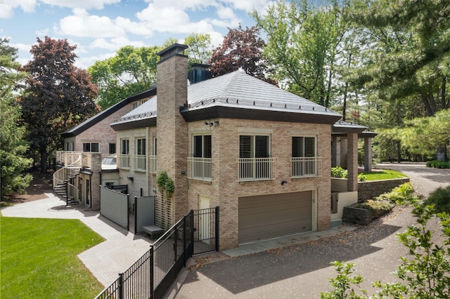 5123 Lake Ridge Rd, Edina, MN 55436 - view of side of property with an attached garage, a chimney, brick siding, driveway, and a gate