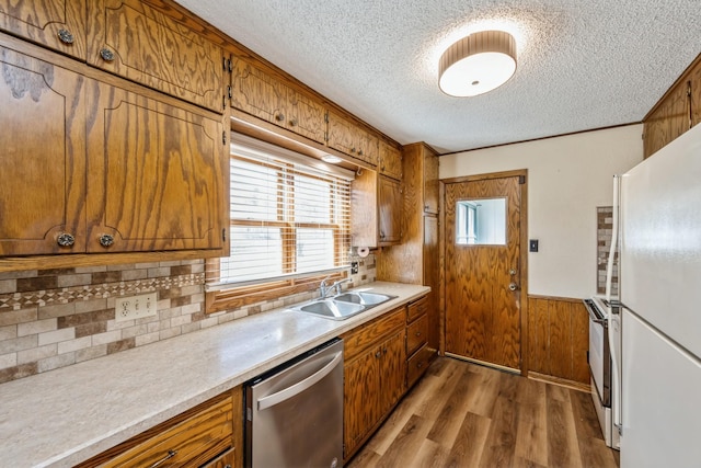 kitchen with a sink, white appliances, light wood-style floors, and brown cabinets