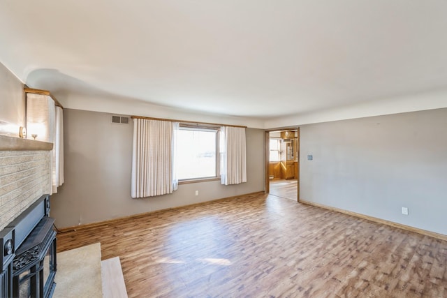 unfurnished living room with visible vents, baseboards, light wood-style flooring, and a fireplace