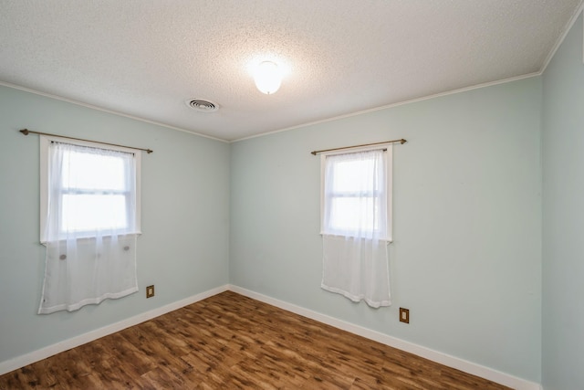 spare room with visible vents, plenty of natural light, baseboards, and dark wood-style flooring