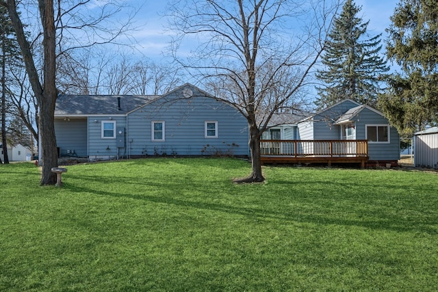 back of house with a deck, a yard, and a shingled roof