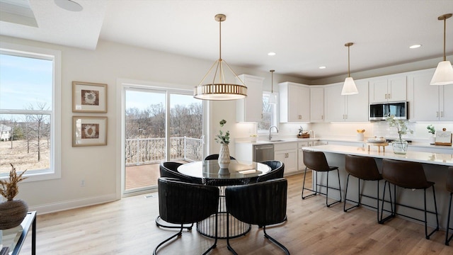 kitchen with light wood finished floors, appliances with stainless steel finishes, a breakfast bar area, and light countertops