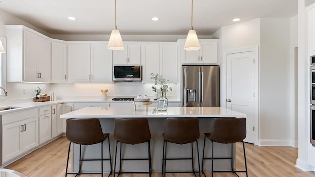 kitchen with a sink, stainless steel appliances, a kitchen island, and light wood finished floors