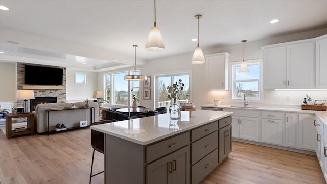 kitchen featuring a sink, light wood finished floors, a center island, and light countertops