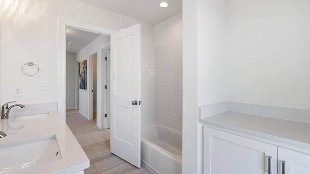 bathroom with double vanity, bathing tub / shower combination, and a sink