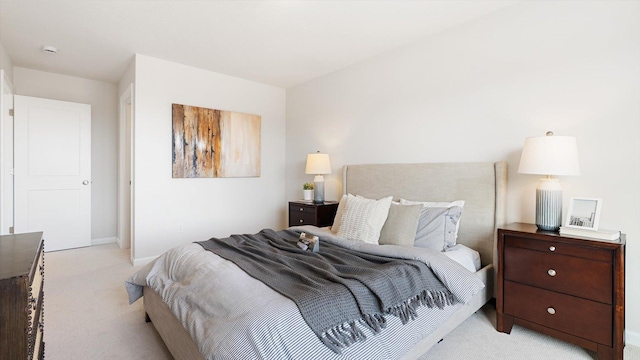 bedroom featuring light colored carpet and baseboards