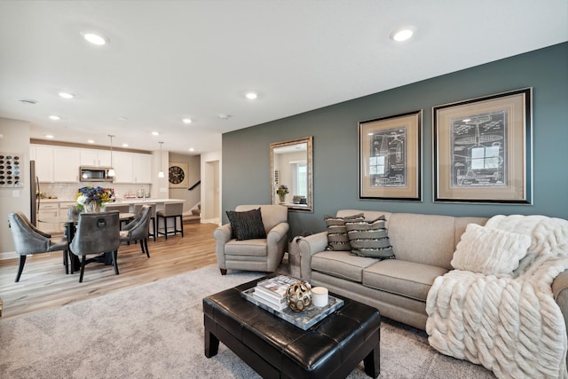 living area with recessed lighting, baseboards, stairs, and light wood finished floors