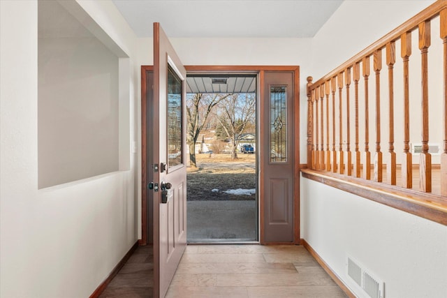 foyer entrance featuring light wood-style floors, baseboards, and visible vents