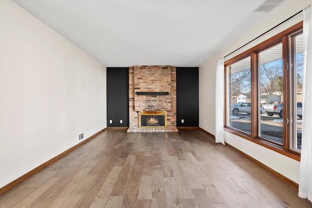 unfurnished living room featuring visible vents, baseboards, wood finished floors, and a fireplace