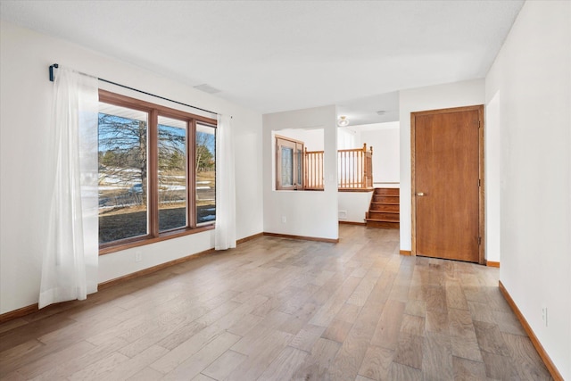 unfurnished room featuring light wood finished floors, stairway, visible vents, and baseboards