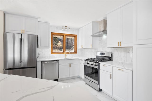 kitchen with light stone counters, a sink, stainless steel appliances, wall chimney range hood, and marble finish floor