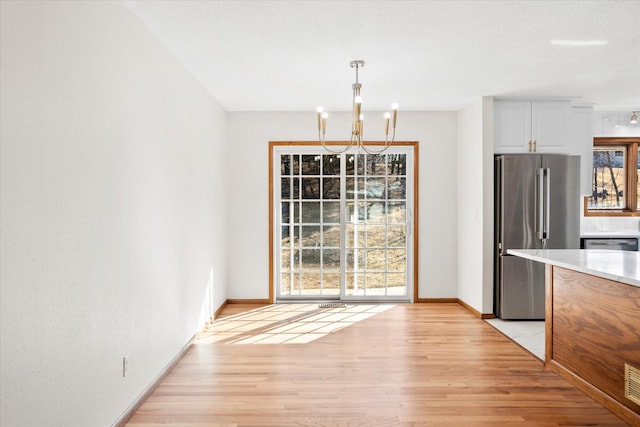 unfurnished dining area featuring visible vents, an inviting chandelier, baseboards, and light wood-style floors