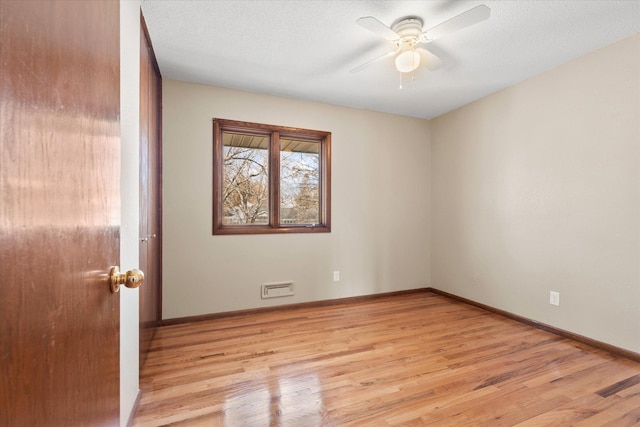 empty room with ceiling fan, baseboards, a textured ceiling, and light wood-style flooring