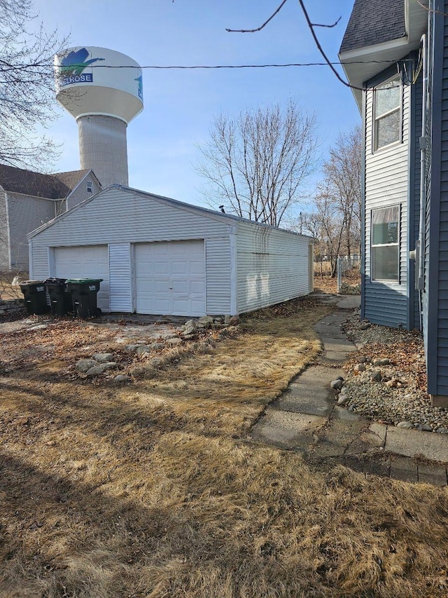 view of side of property featuring a garage, a shingled roof, and an outdoor structure