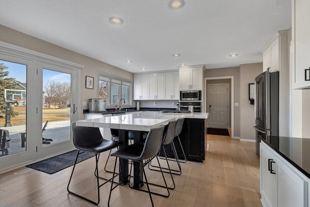 kitchen featuring stainless steel appliances, a breakfast bar area, a center island, and white cabinetry