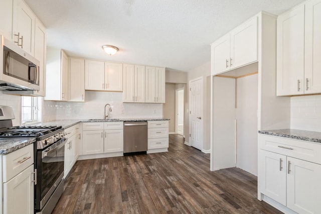 kitchen featuring light stone counters, dark wood-style floors, a sink, stainless steel appliances, and tasteful backsplash