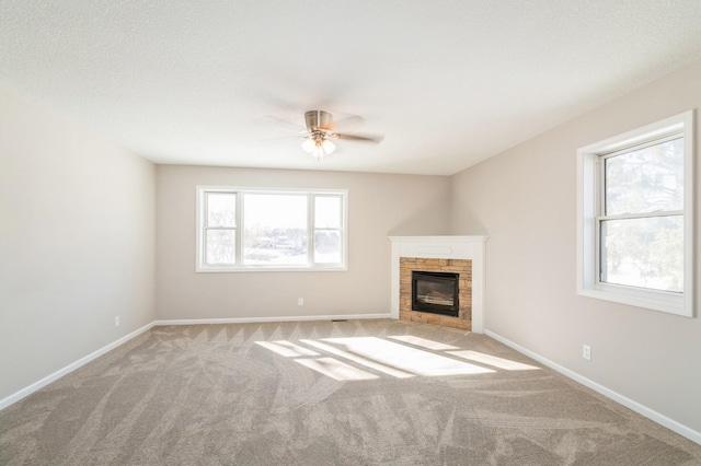 unfurnished living room featuring a fireplace with flush hearth, baseboards, carpet, and a ceiling fan