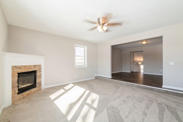 unfurnished living room with a fireplace, baseboards, carpet, and a ceiling fan