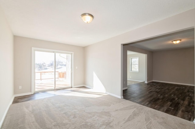 unfurnished room featuring dark wood-style flooring, baseboards, and dark carpet