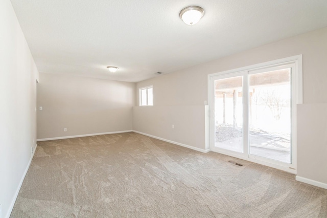 spare room with carpet flooring, baseboards, and visible vents