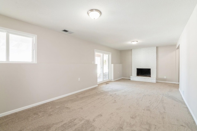 unfurnished living room with baseboards, visible vents, light carpet, and a brick fireplace