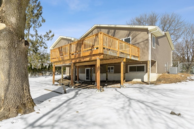 snow covered rear of property featuring a wooden deck and cooling unit