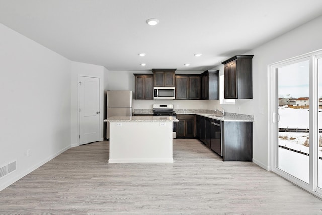 kitchen with a kitchen island, light wood-style flooring, a sink, stainless steel appliances, and dark brown cabinetry